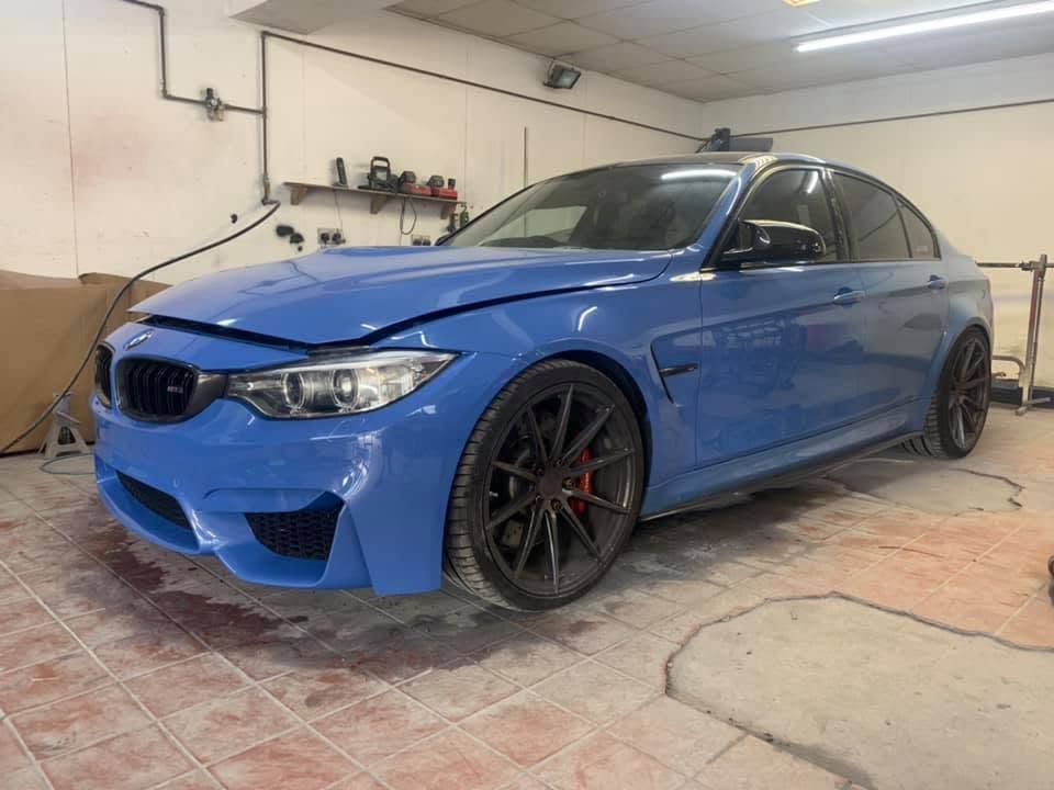 Finished blue BMW M3 respray photographed from the front three quarter inside the workshop